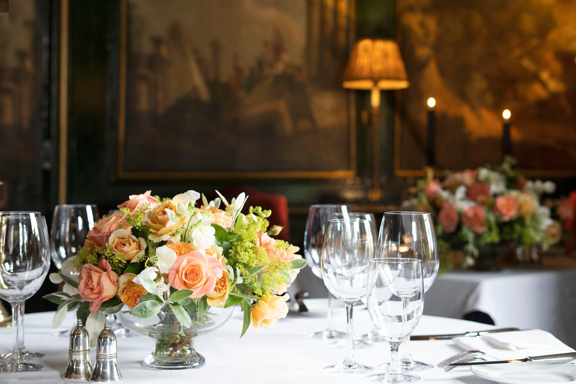 Bouquet of flowers and wine glasses on table with paintings in Edinburgh restaurant private rooms