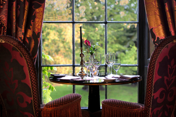 Table set with wine glasses looking out of window at the estate and gardens at Prestonfield House 5 star hotel near Edinburgh