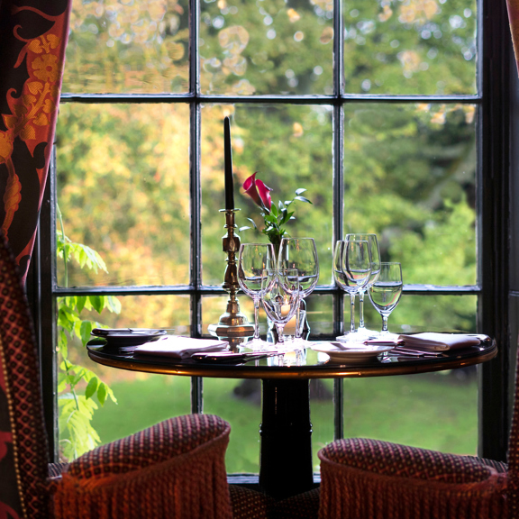 Table set with wine glasses looking out of window at the estate and gardens at Prestonfield House 5 star hotel near Edinburgh
