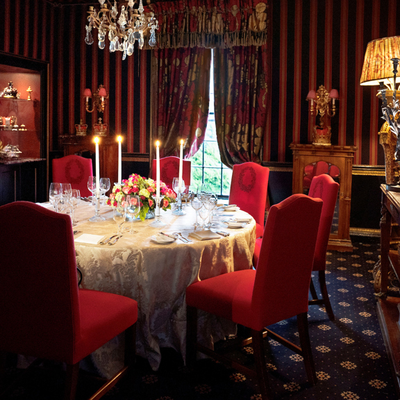 Candles lit and table set with red velvet background in The Stuart private dining room in Edinburgh at Prestonfield House 