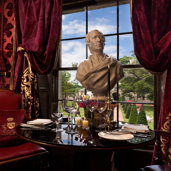 Set table with marble bust and red velvet decor in The Salon Privee small private dining room at Prestonfield House Edinburgh